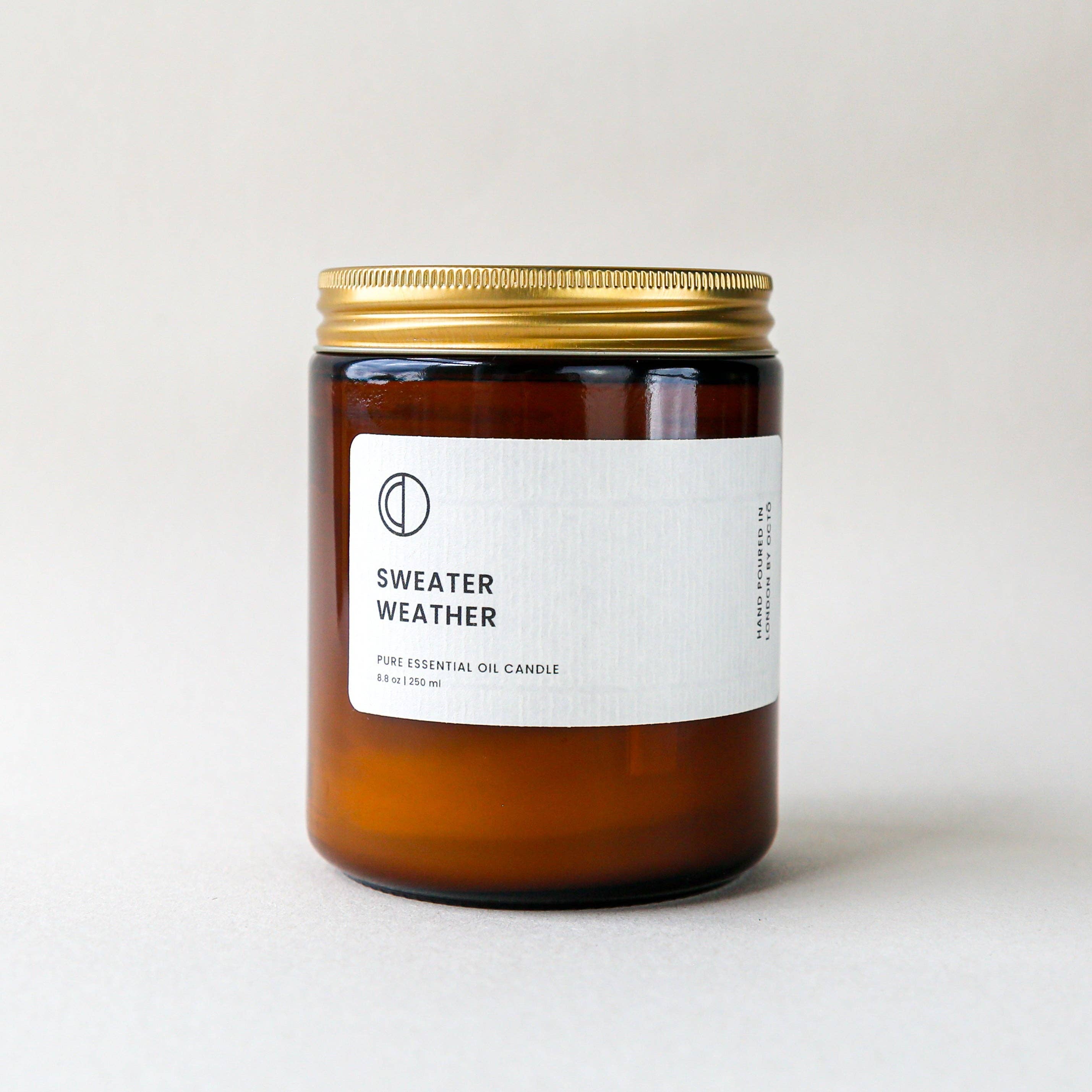 Candle labeled 'Sweater Weather' with a gold lid on a light background