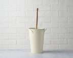 Beige bucket against a white brick wall.
