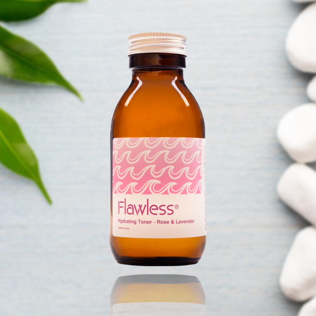 Brown bottle with pink label featuring 'Flawless' on a light gray background with green leaves and white stones.
