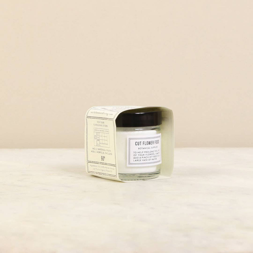 Cut flower food in a glass jar with a black lid on a beige background