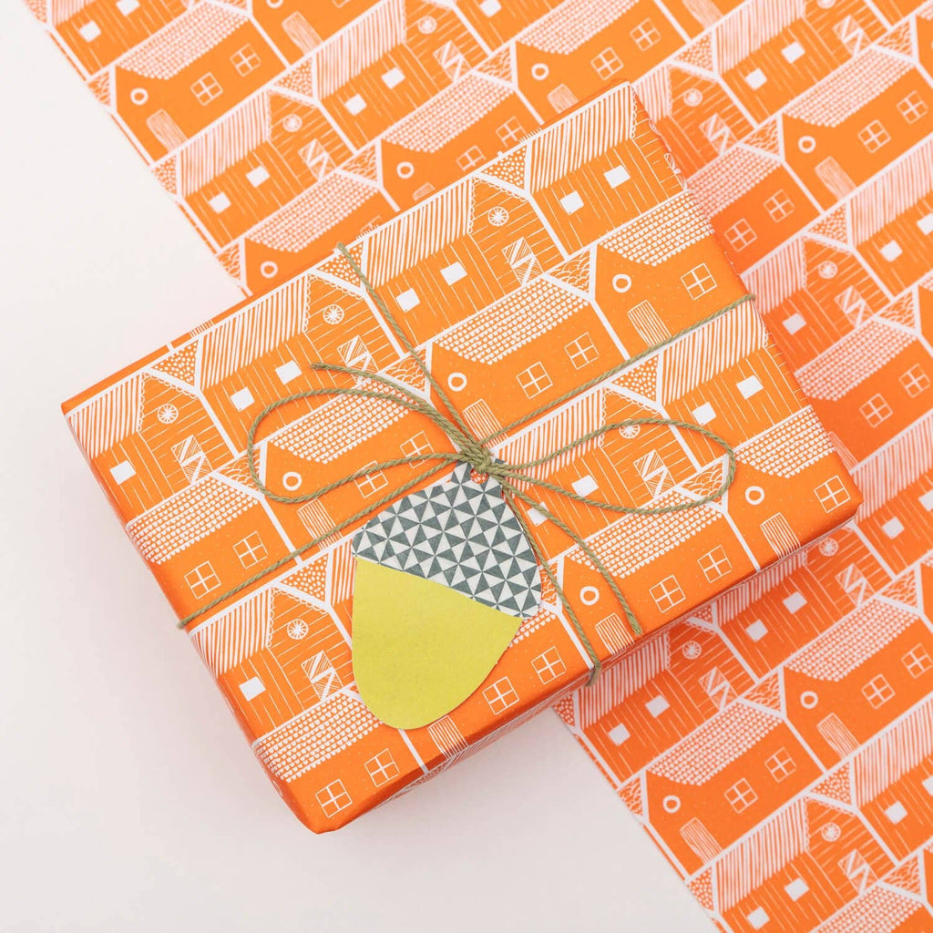 Gift box with orange patterned paper and a green tag on a white background