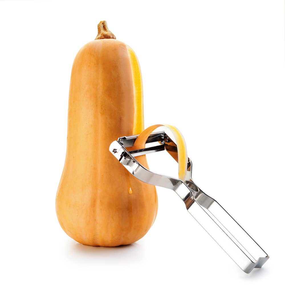 Butternut squash with a metal peeler on a white background