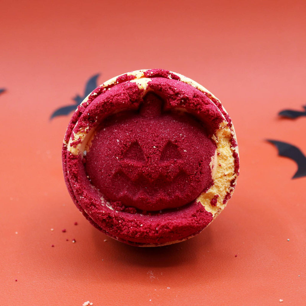 Halloween-themed bath additive with red center and pumpkin face on orange background