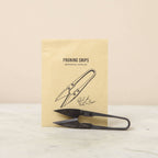 Pruning shears with a branded paper bag on a light background