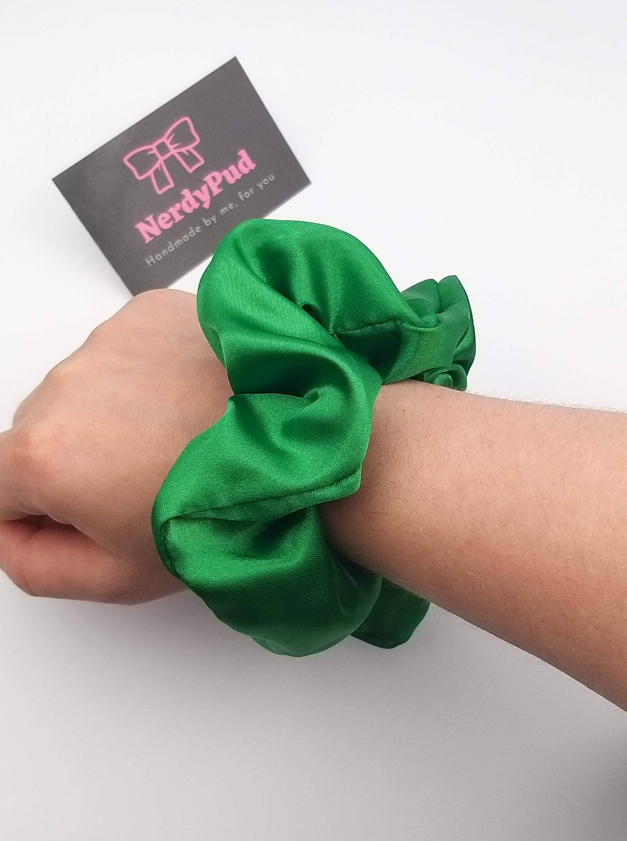 Green scrunchie on a wrist with Nerdypud branding in the background