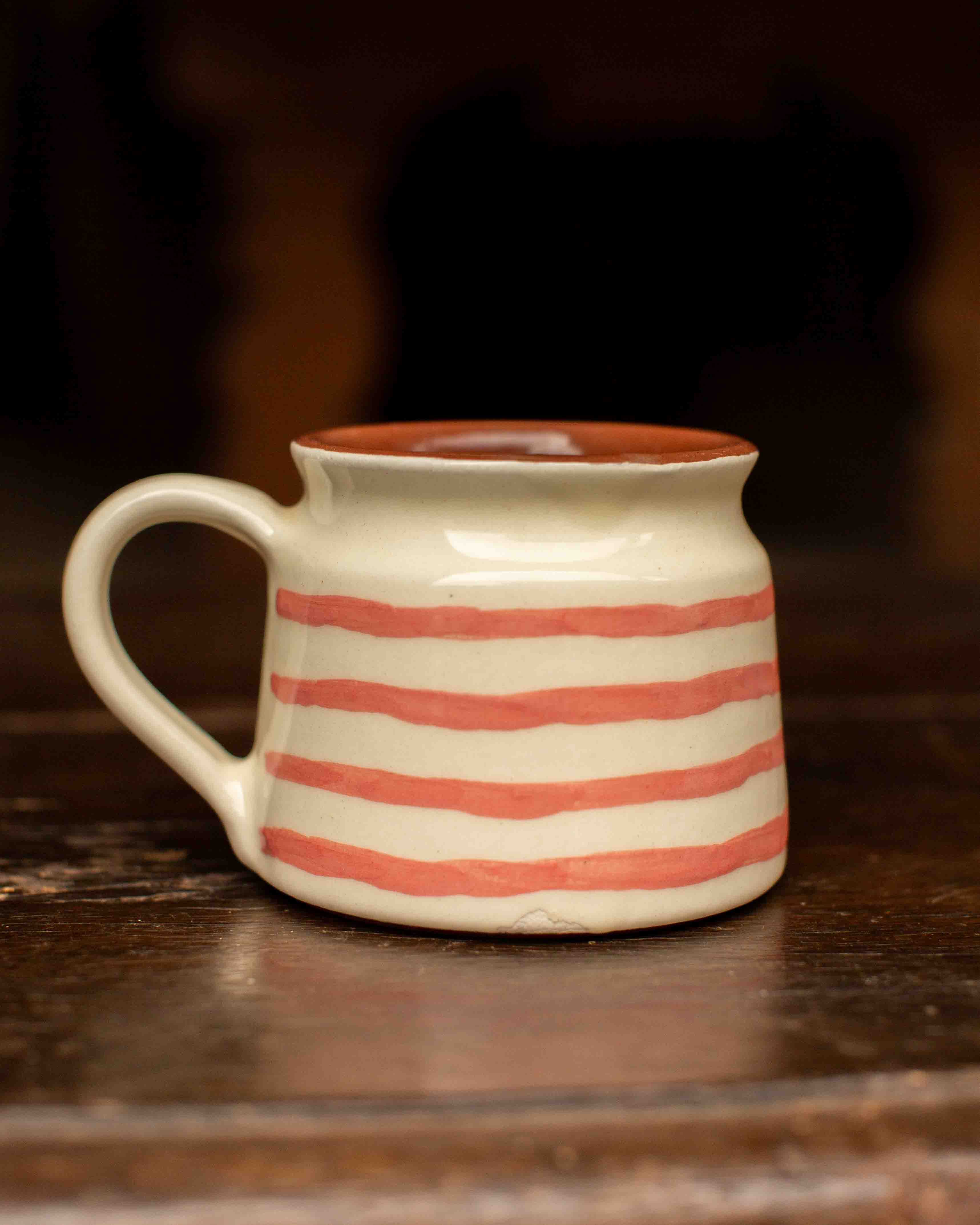 White mug with red stripes on a wooden surface