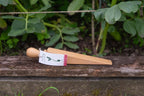 Wooden door wedge on a wooden surface with greenery in the background