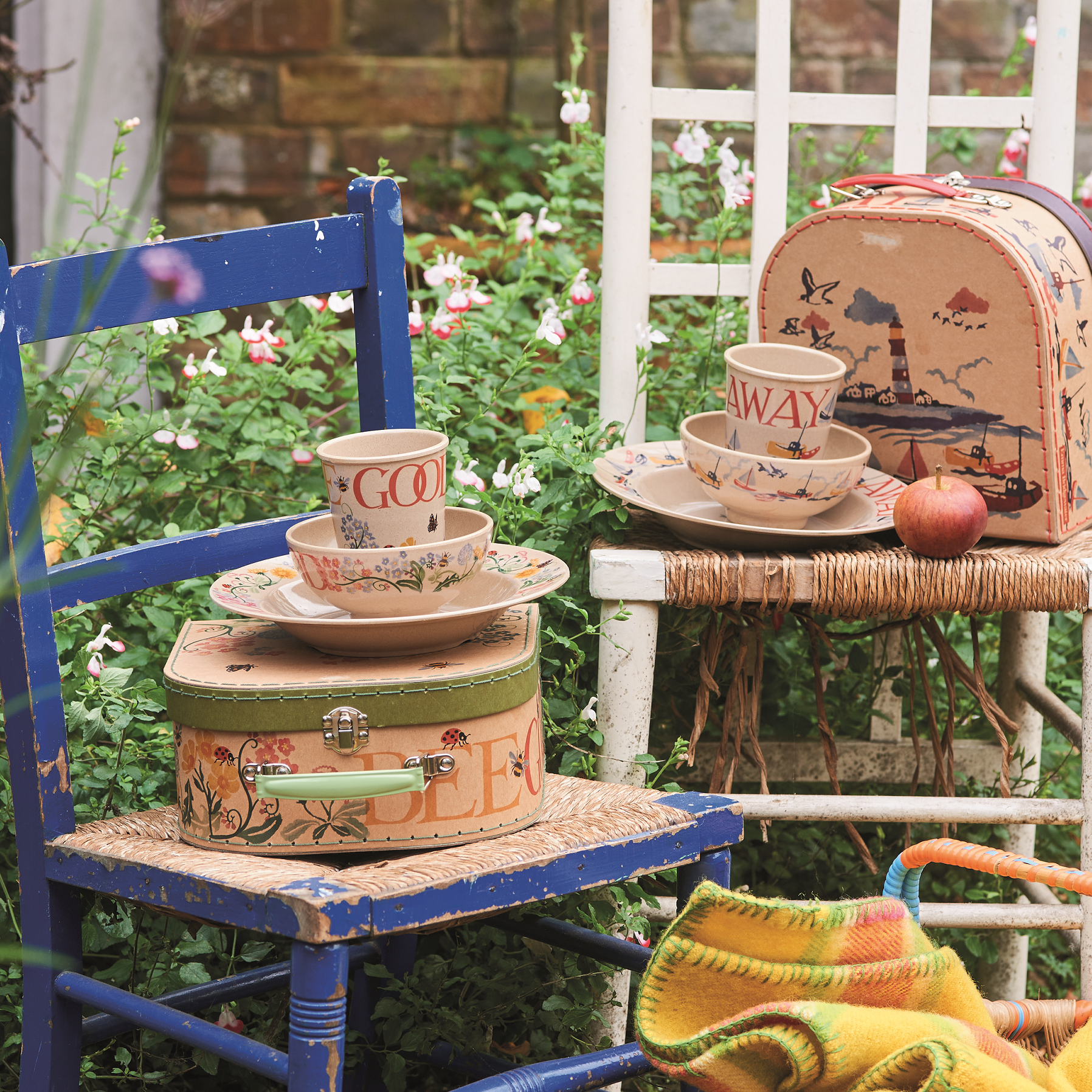 Vintage suitcases with tea set on a blue chair in a garden setting