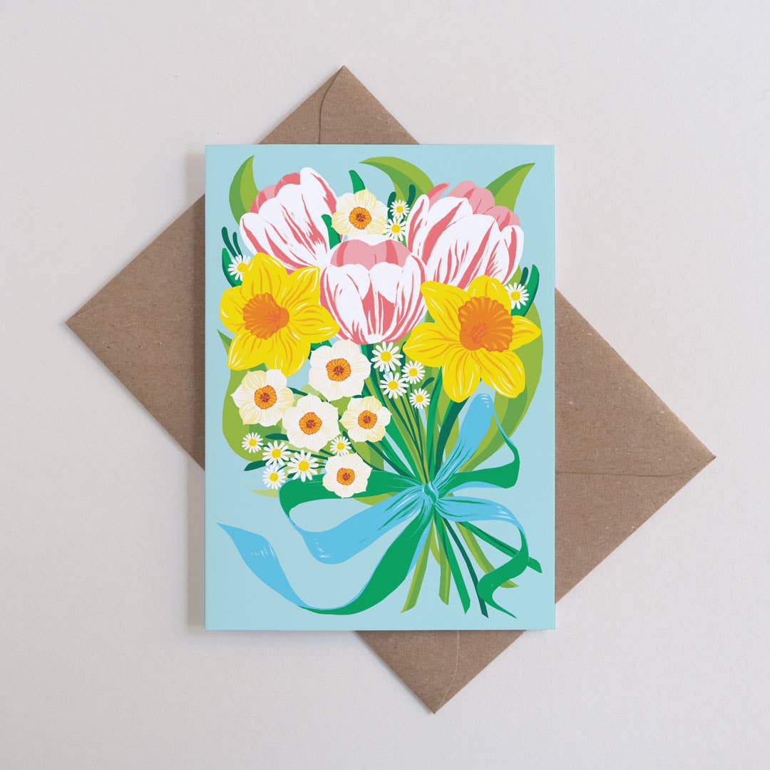 Greeting card with floral design on a light blue background, placed on a brown envelope.