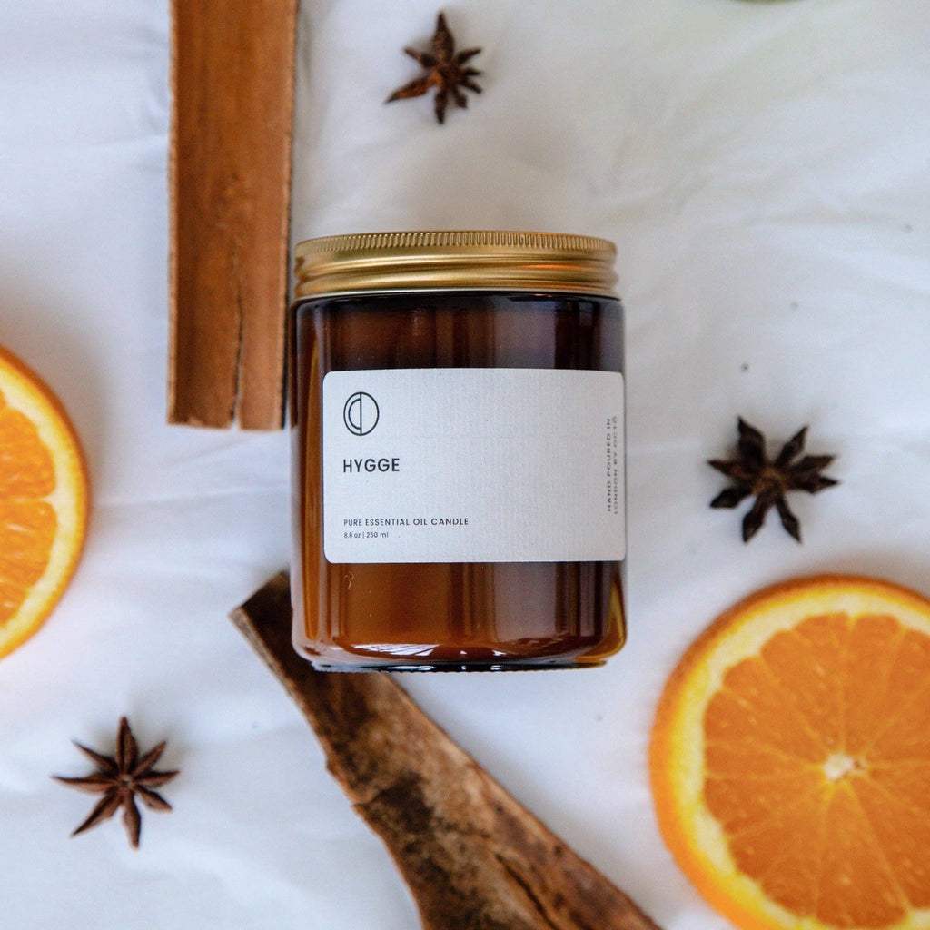 Hygge candle jar with cinnamon stick and orange slices on a white background