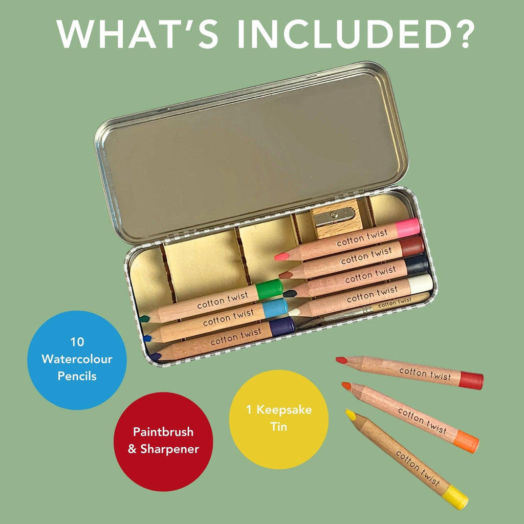 Set of watercolor pencils in a keepsake tin with a paintbrush and sharpener on a green background.
