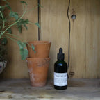 Bottle of indoor plant food with potted plants on a wooden surface