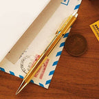 Gold pen on a wooden surface with an envelope and coin