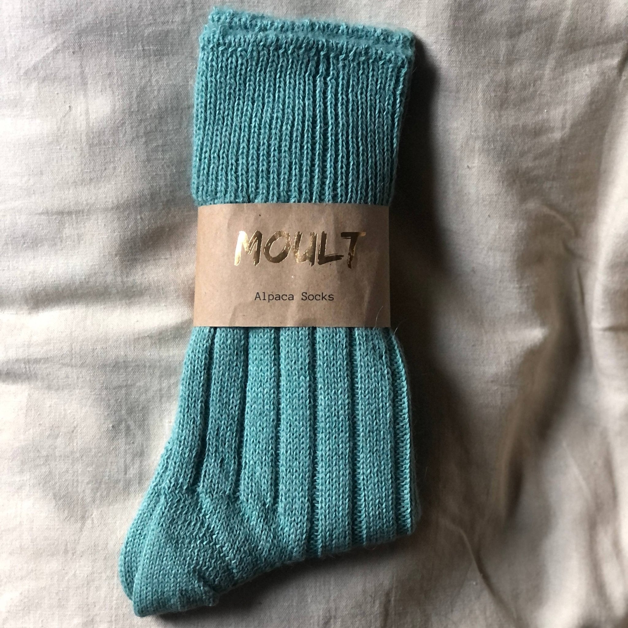 Alpaca Socks In Teal with card label on cream linen background