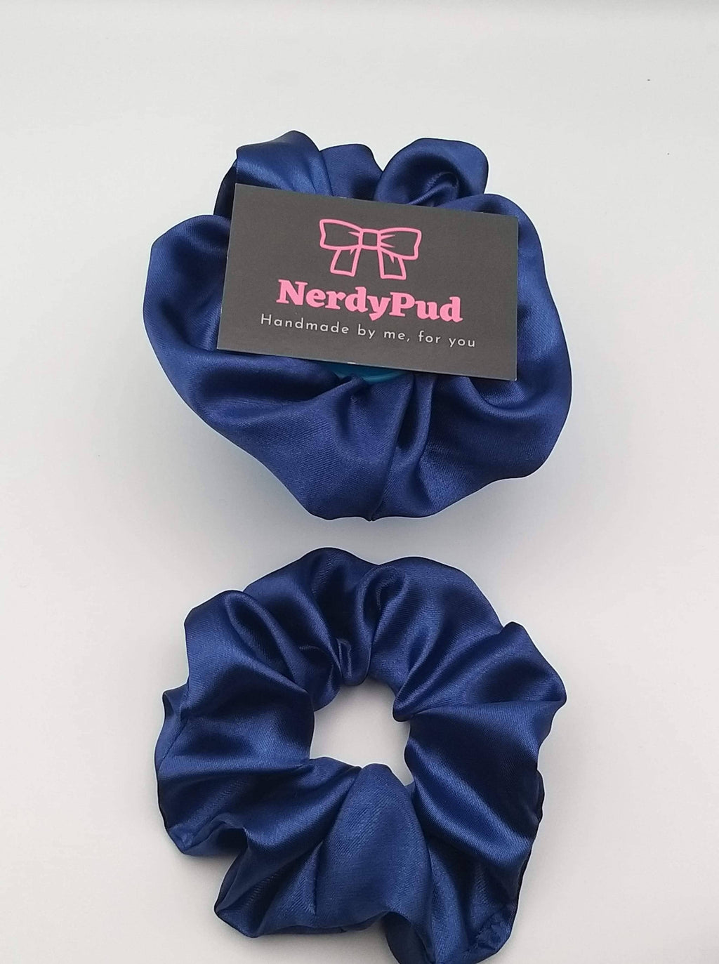 Two blue scrunchies with a 'NerdyPud' branded card on a white background