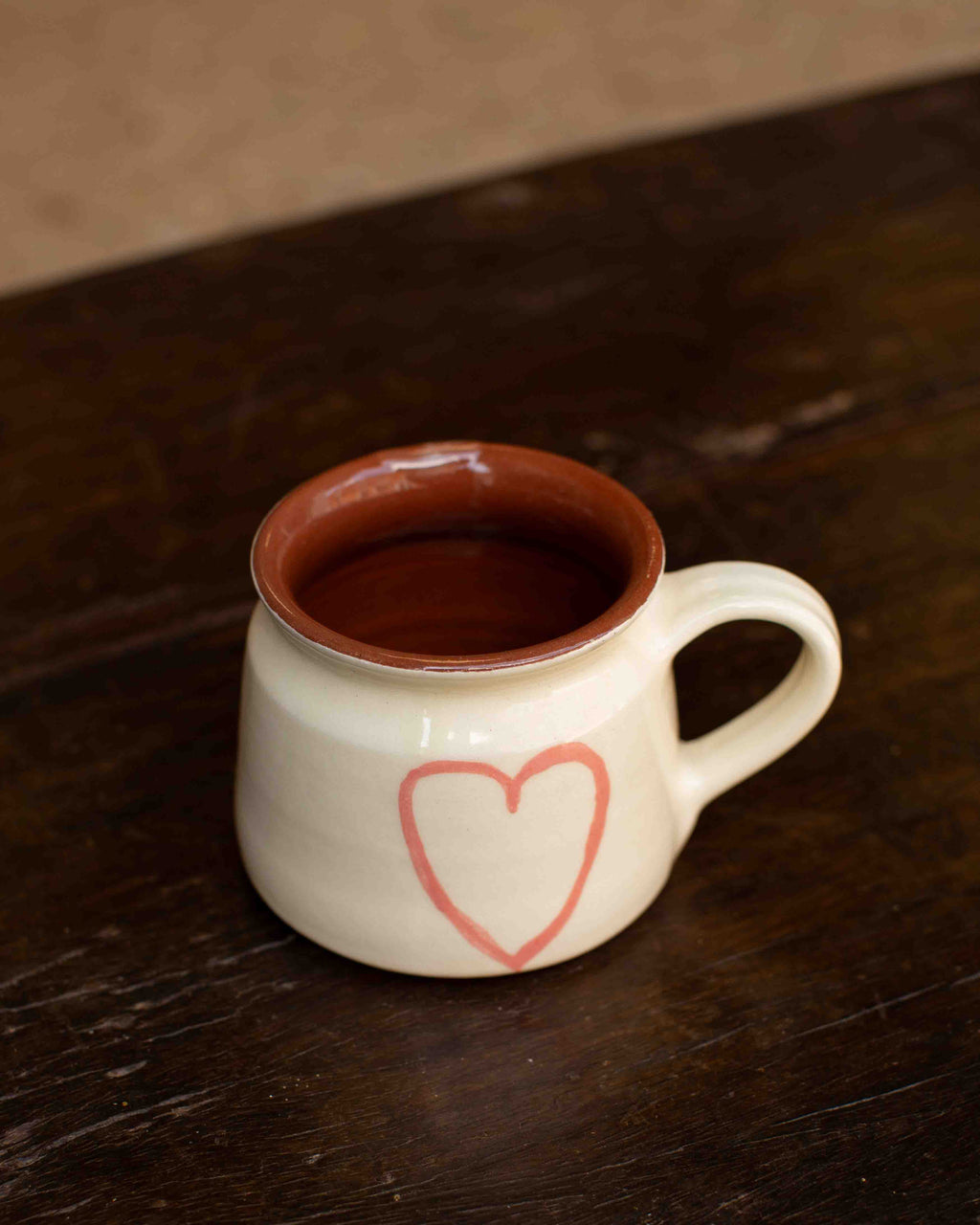 Ceramic mug with a heart design on a wooden surface