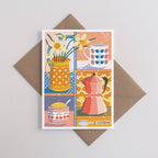 Greeting card with kitchen-themed design featuring a pitcher, cup, and flowers on a brown envelope.