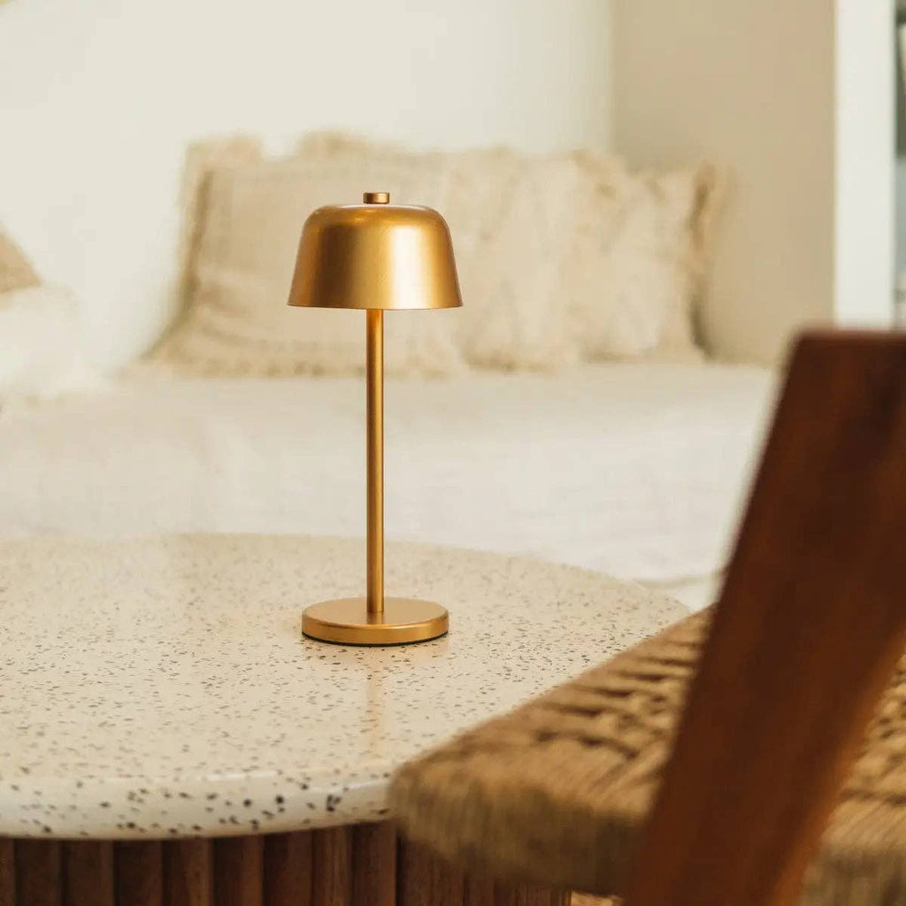 Gold table lamp on a textured surface with a blurred background