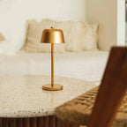 Gold table lamp on a textured surface with a blurred background