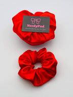Two red scrunchies with a 'NerdyPud' card on a light gray background