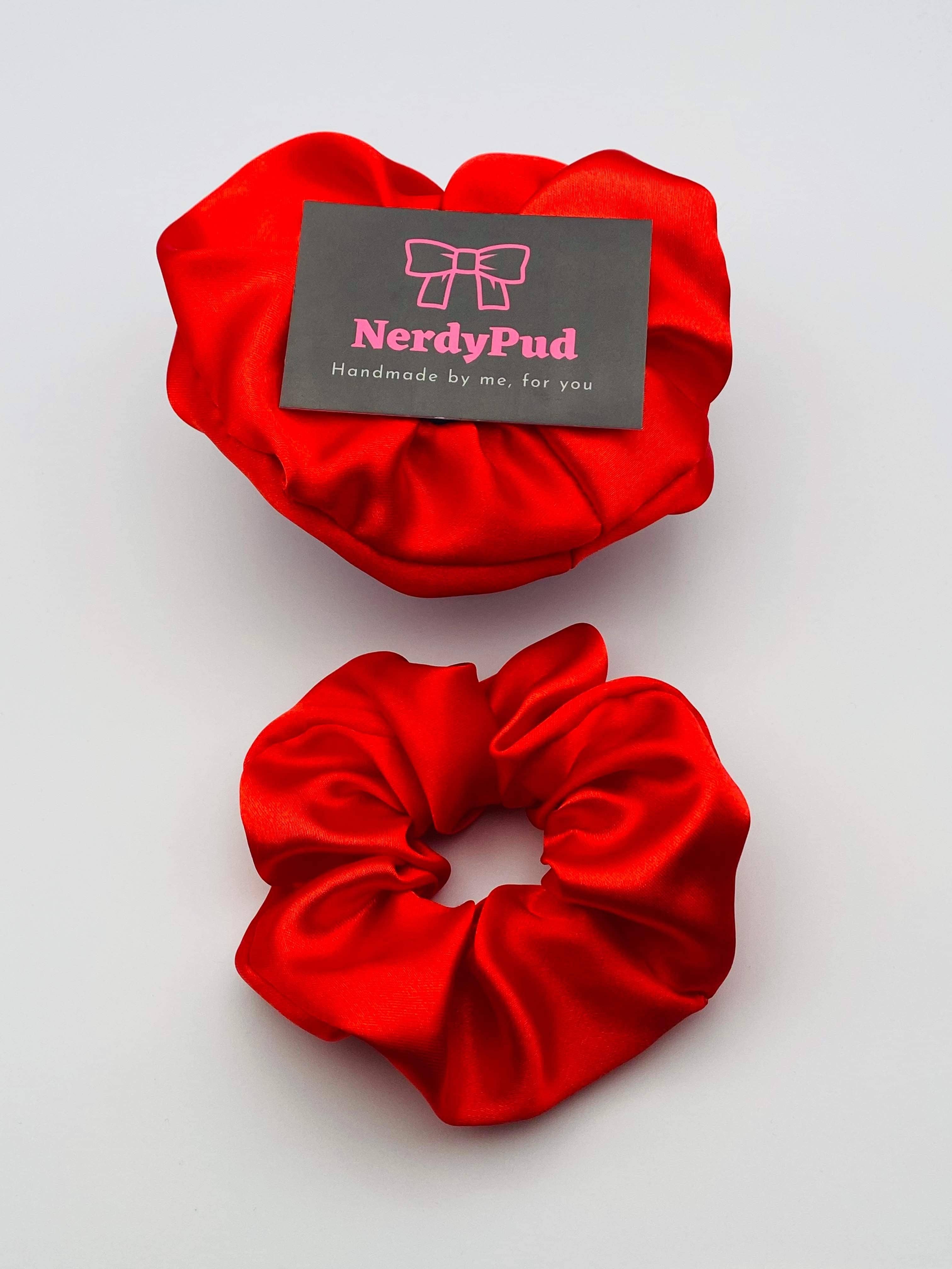 Two red scrunchies with a 'NerdyPud' card on a light gray background