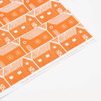 Patterned paper with orange and white house design on a white background