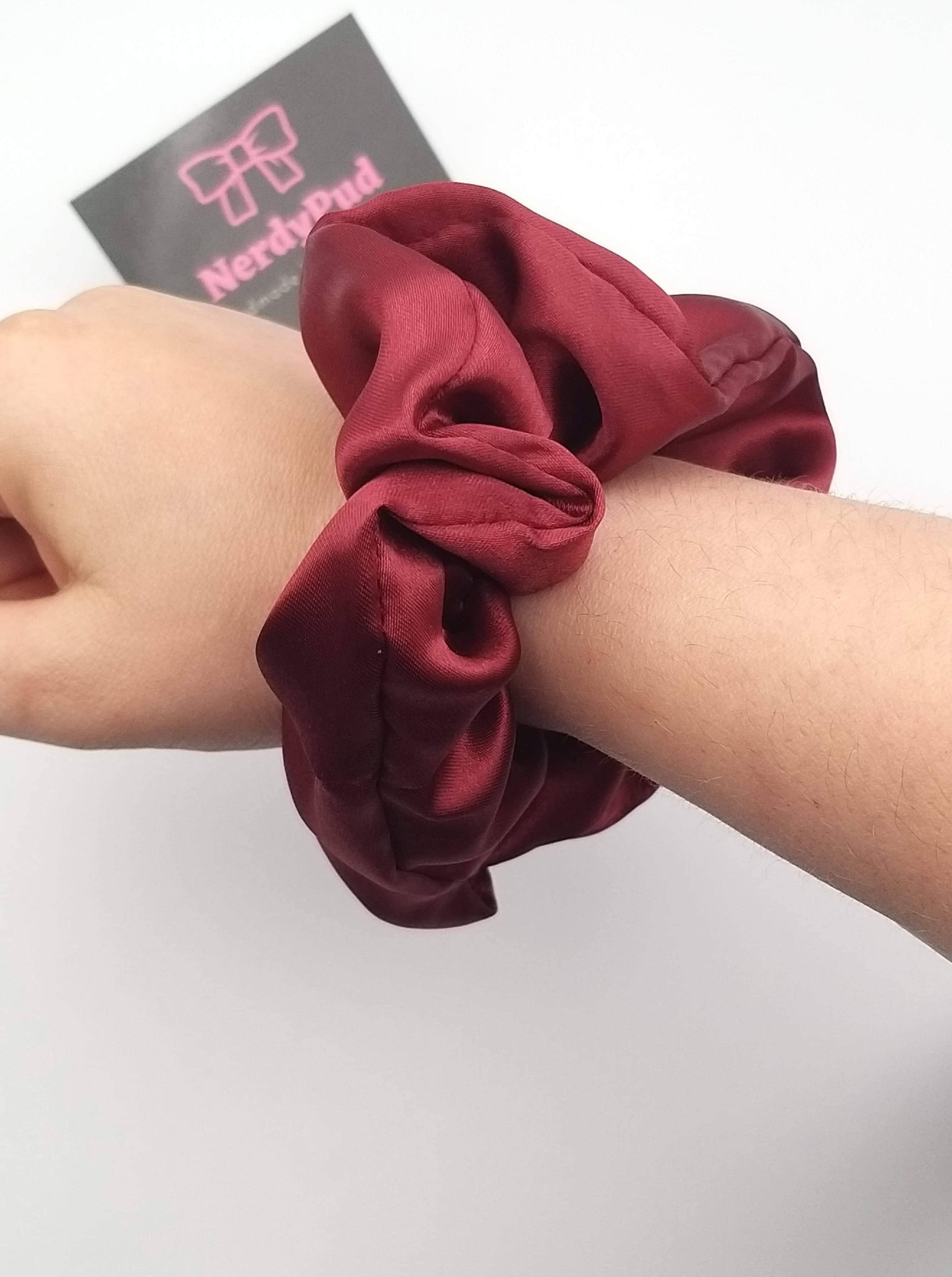 Red scrunchie on a wrist with a white background