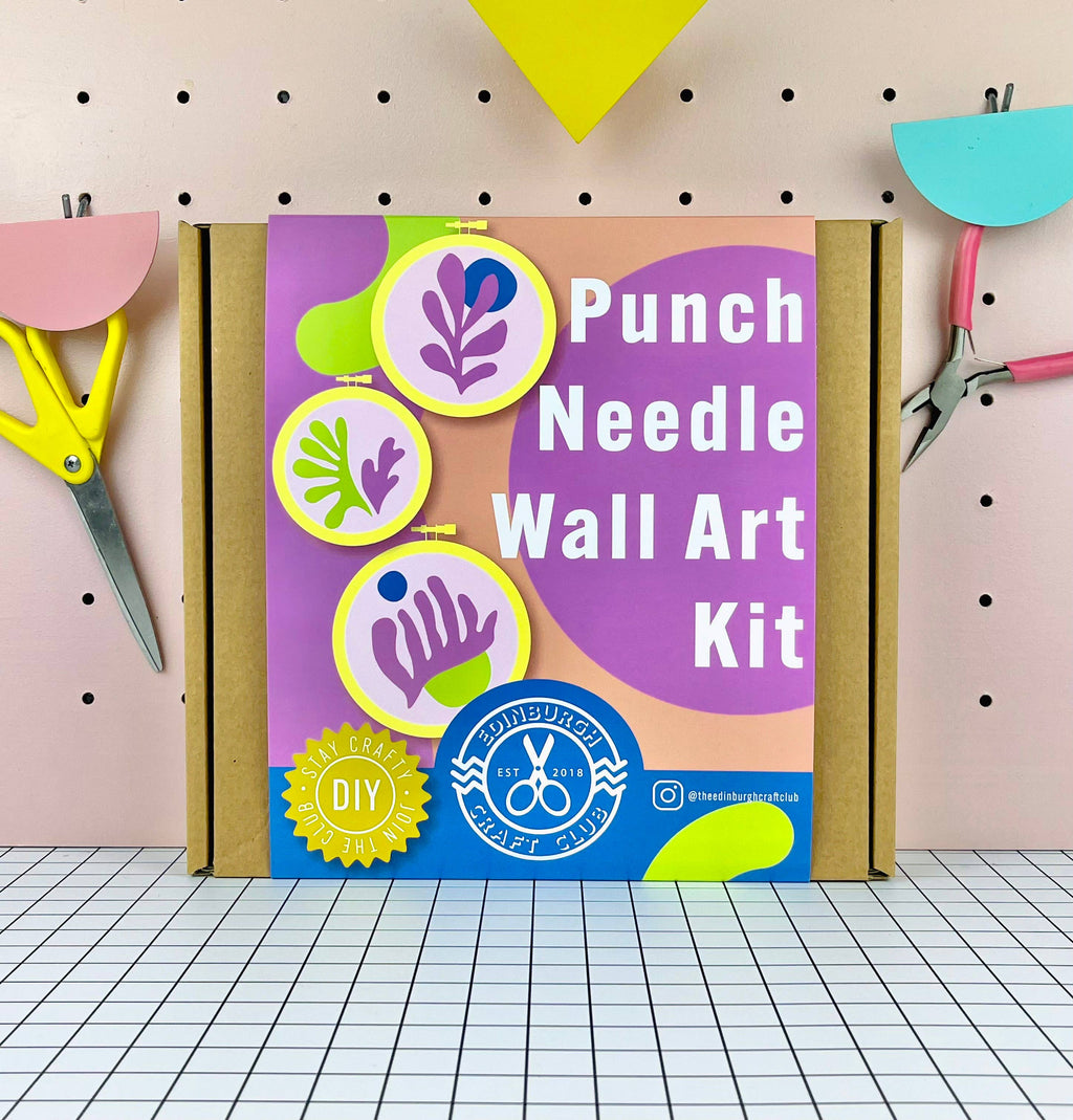 Punch Needle Wall Art Kit packaging with scissors and tools on a pegboard background