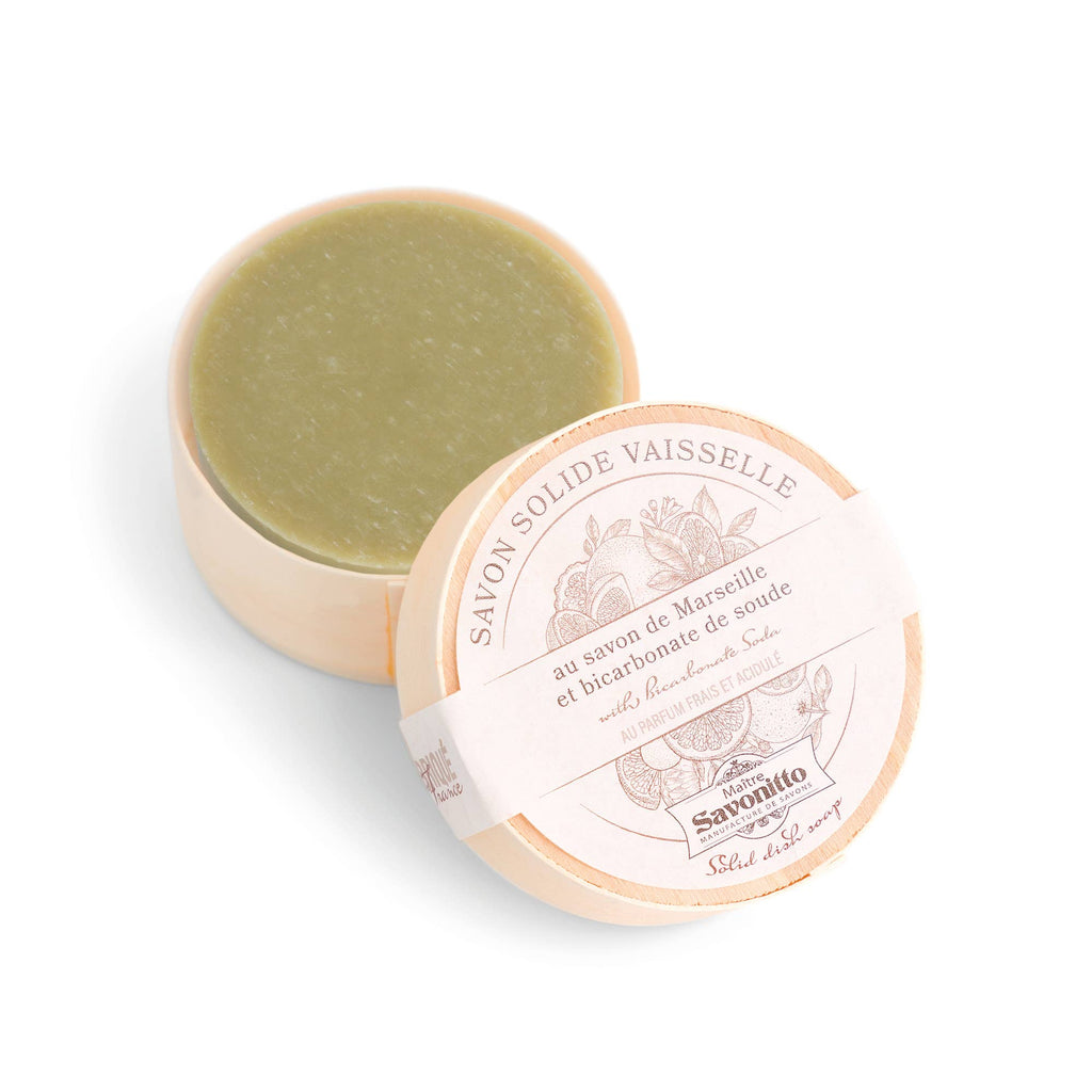 Solid Marseille soap in a round container with a white lid on a light beige background