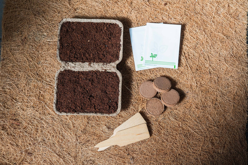 Seed starting trays, peat pads, and a small trowel on a brown surface