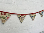 Fabric bunting with geometric patterns on a white textured background