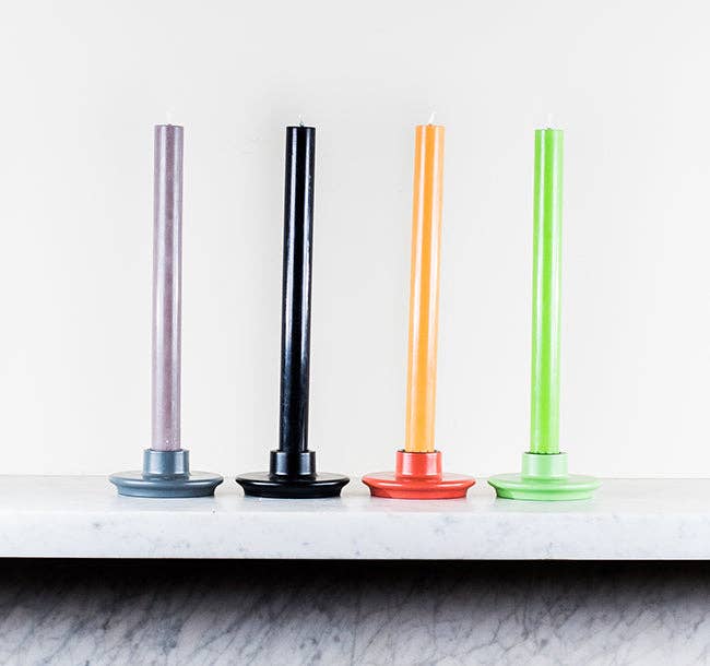 Four colorful candles on a marble surface with a white background