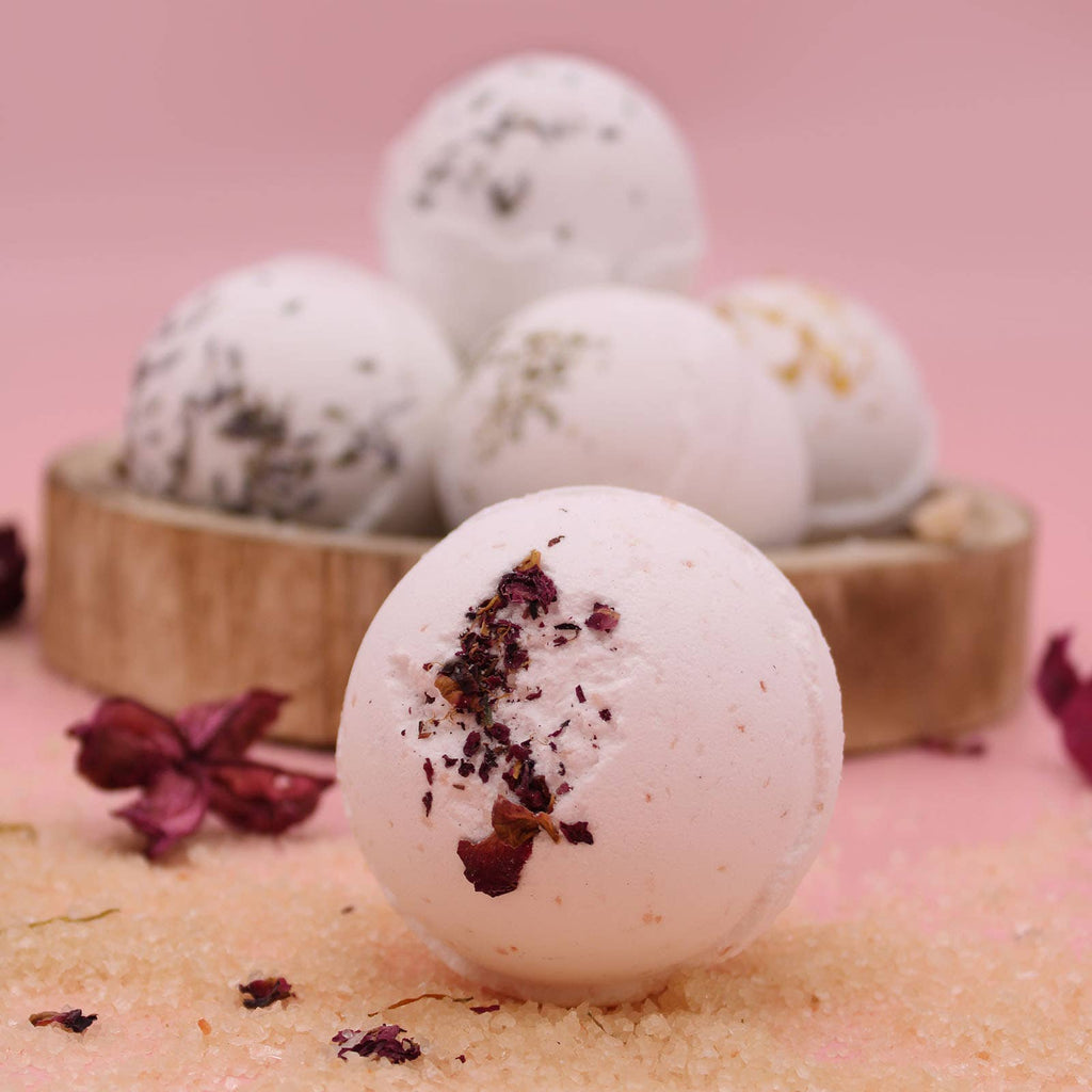 Bath bombs with natural ingredients and rose petals on a pink background