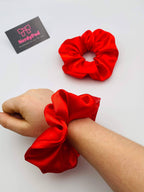 Red scrunchies on a wrist with a 'NerdyPud' business card in the background
