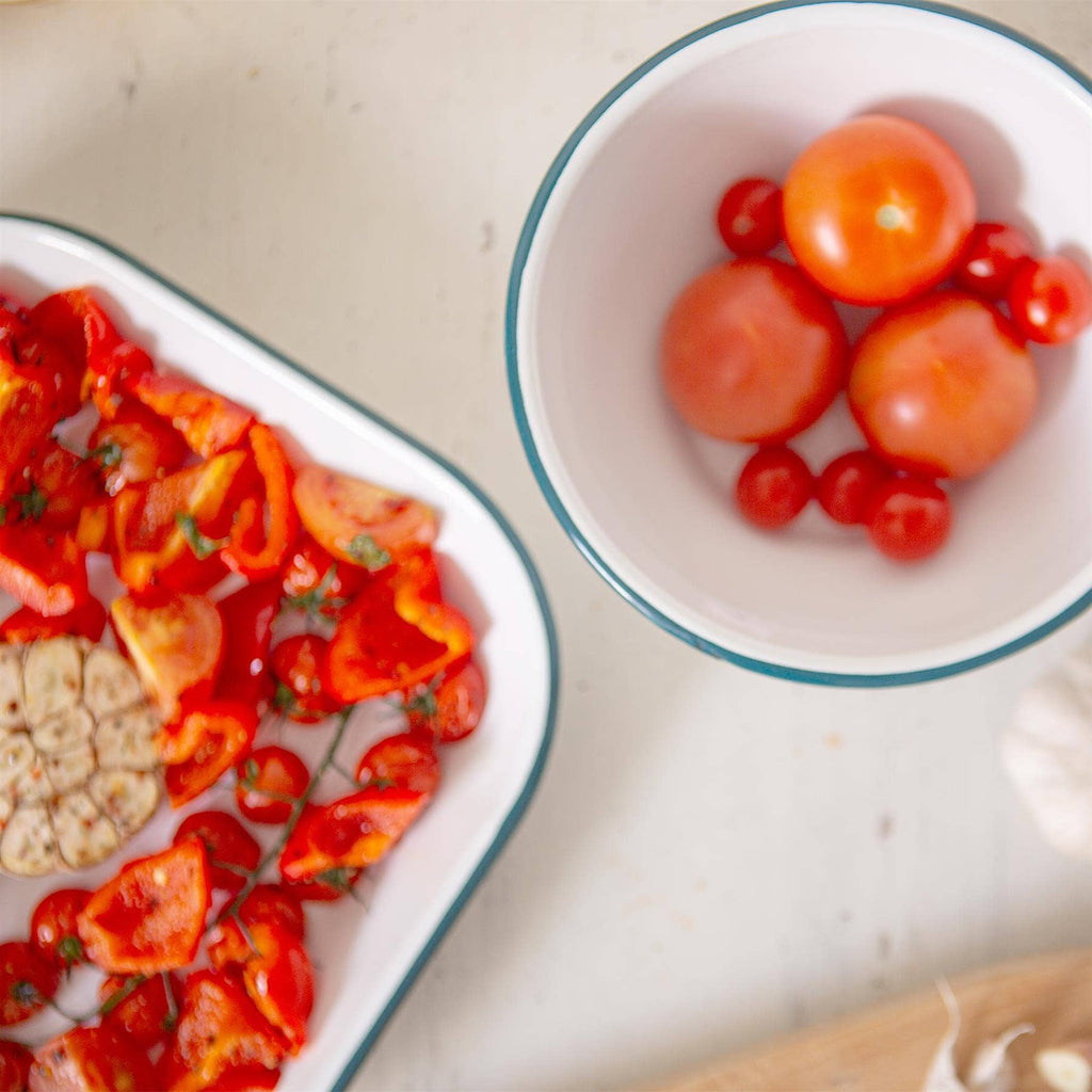 white enamelware tins containing roasting tomatoes peppers and garlic