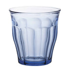 Blue glass tumbler with a textured design on a white background
