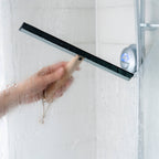 Person cleaning a shower door with a wood handled squeegee