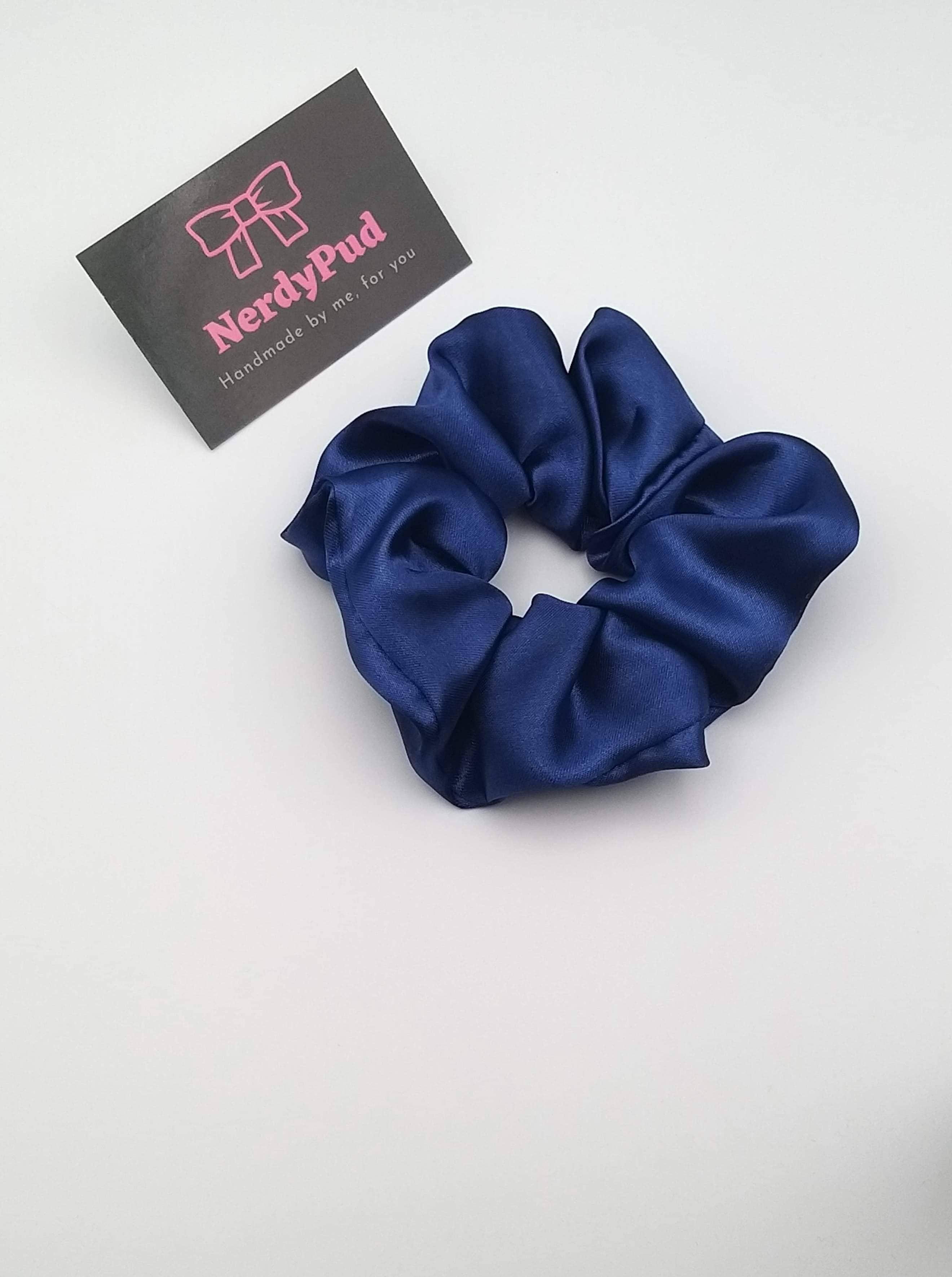 Navy blue scrunchie with a branded card on a white background