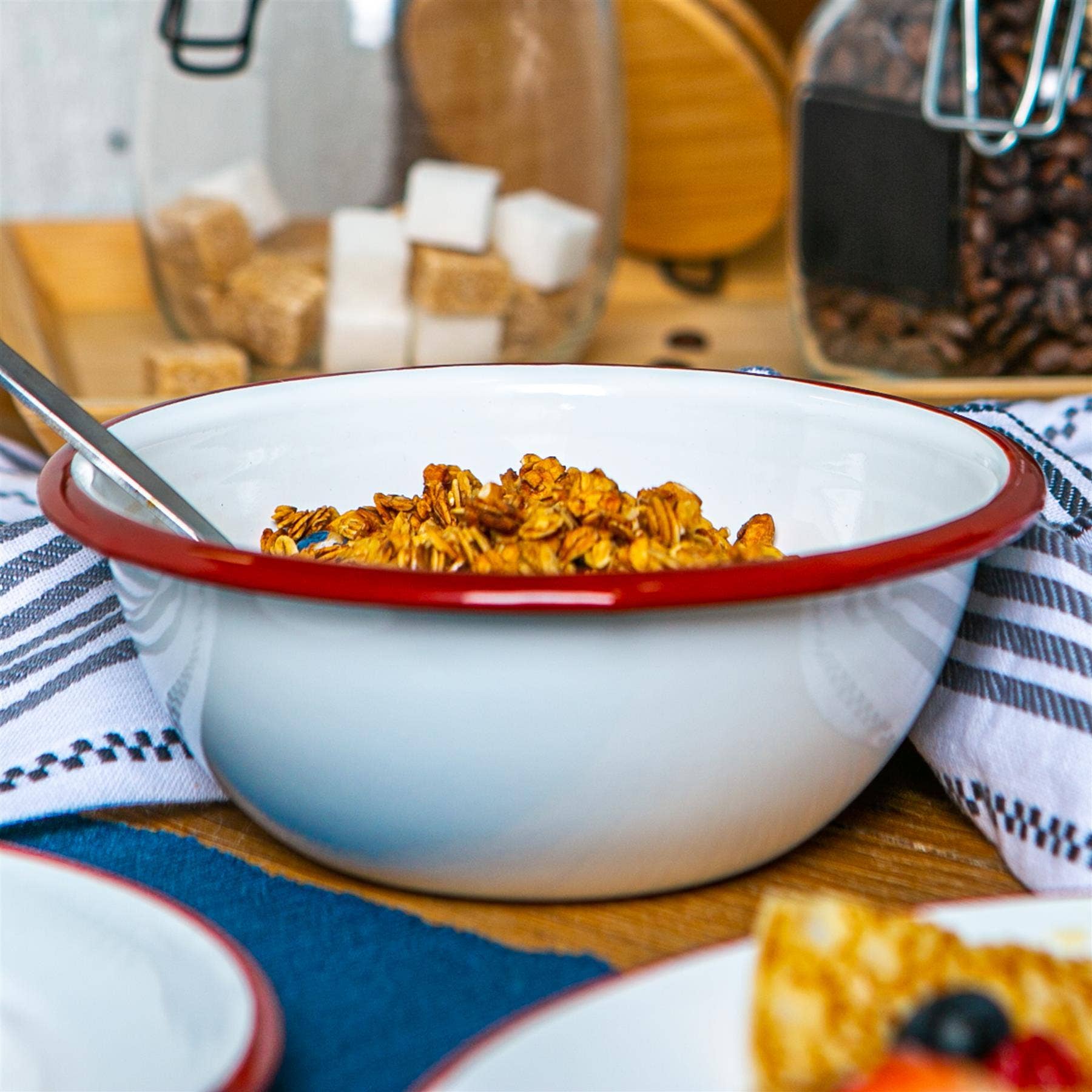 White bowl with red rim containing cereal on a wooden table.
