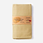 Packaged organic cotton tea towels with a cardboard label on a white background