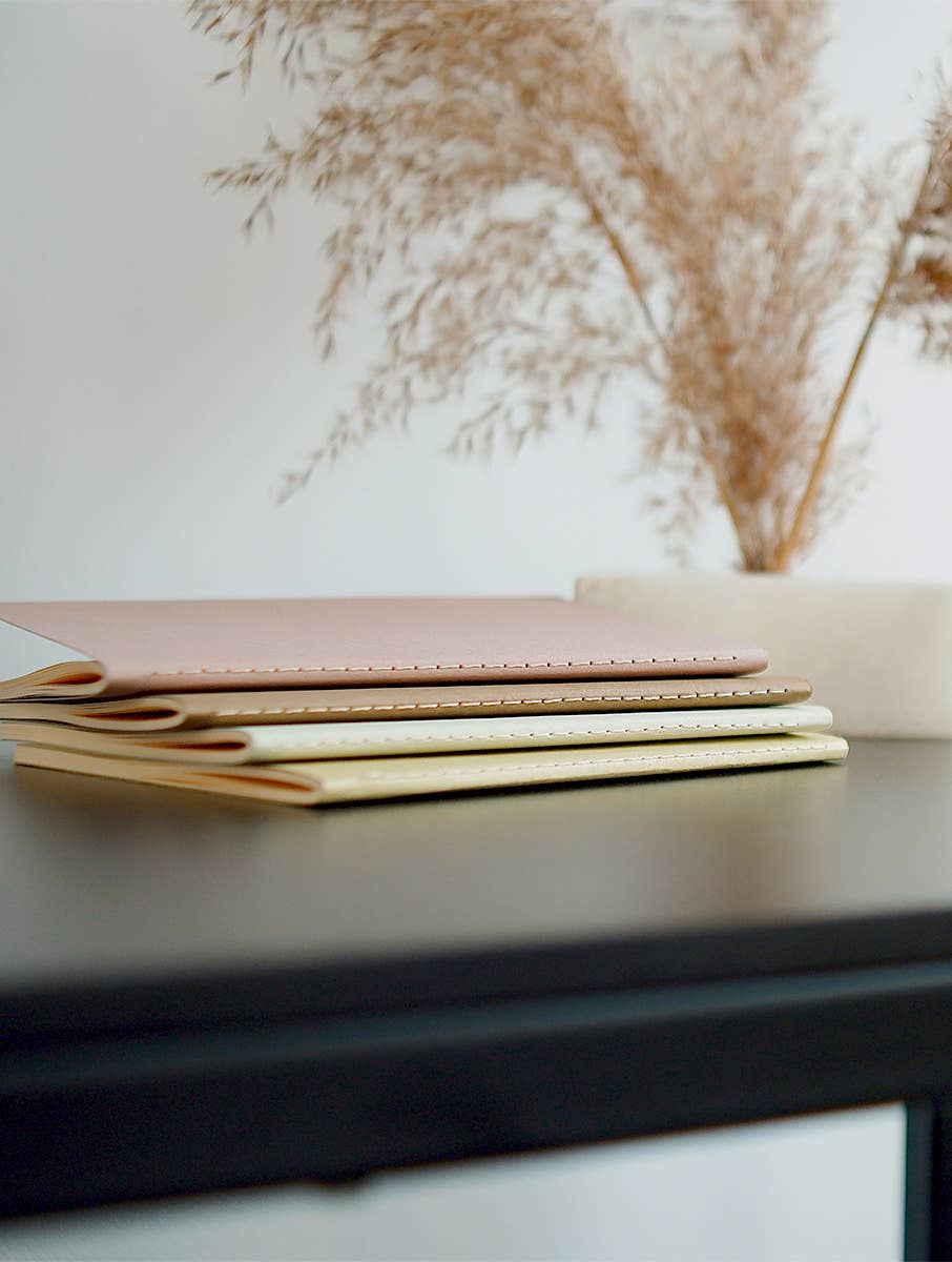 Stack of notebooks on a dark surface with a blurred natural background