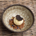 Dessert with ice cream and truffle in a rustic bowl on a woven surface