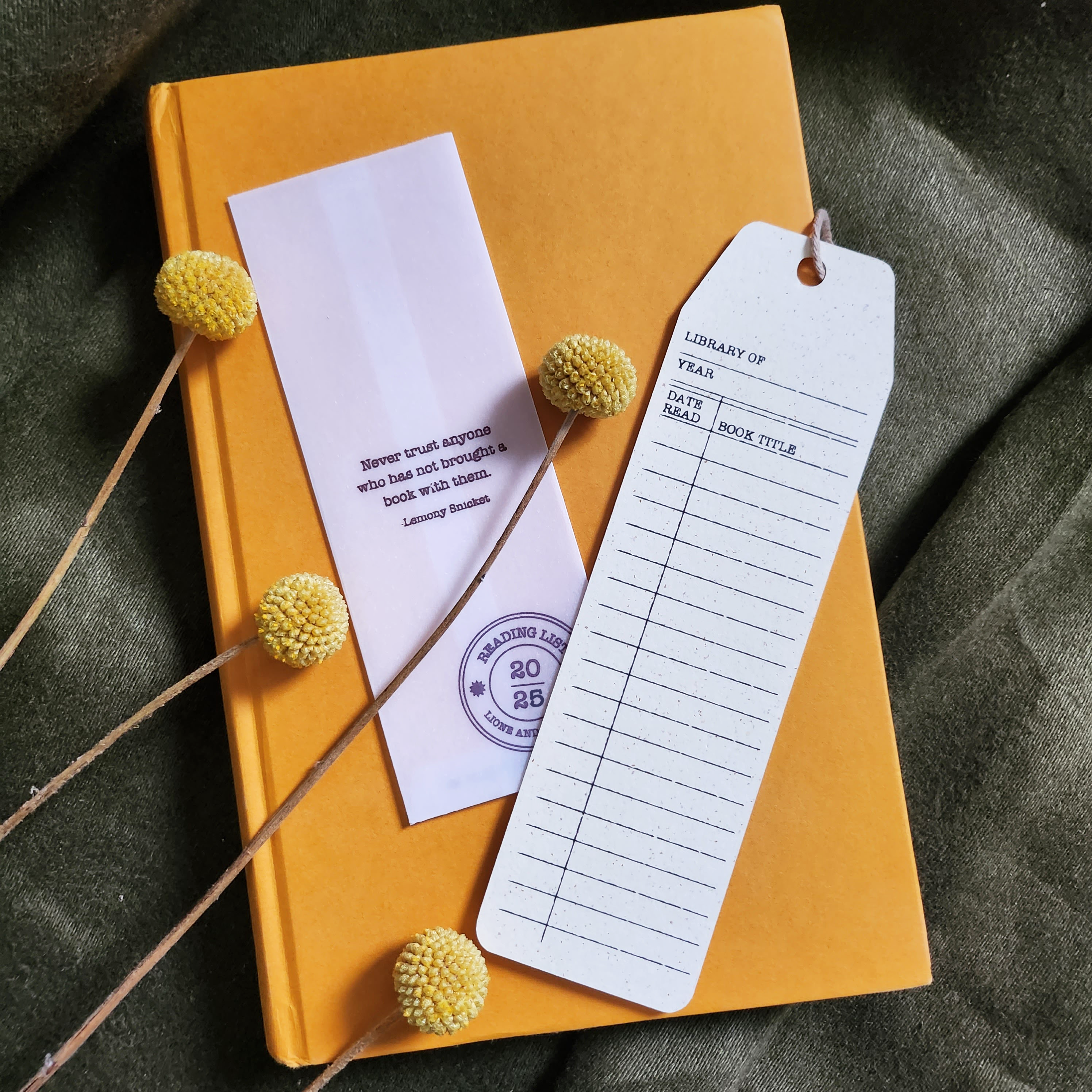 Yellow notebook with a bookmark and library card on a textured surface
