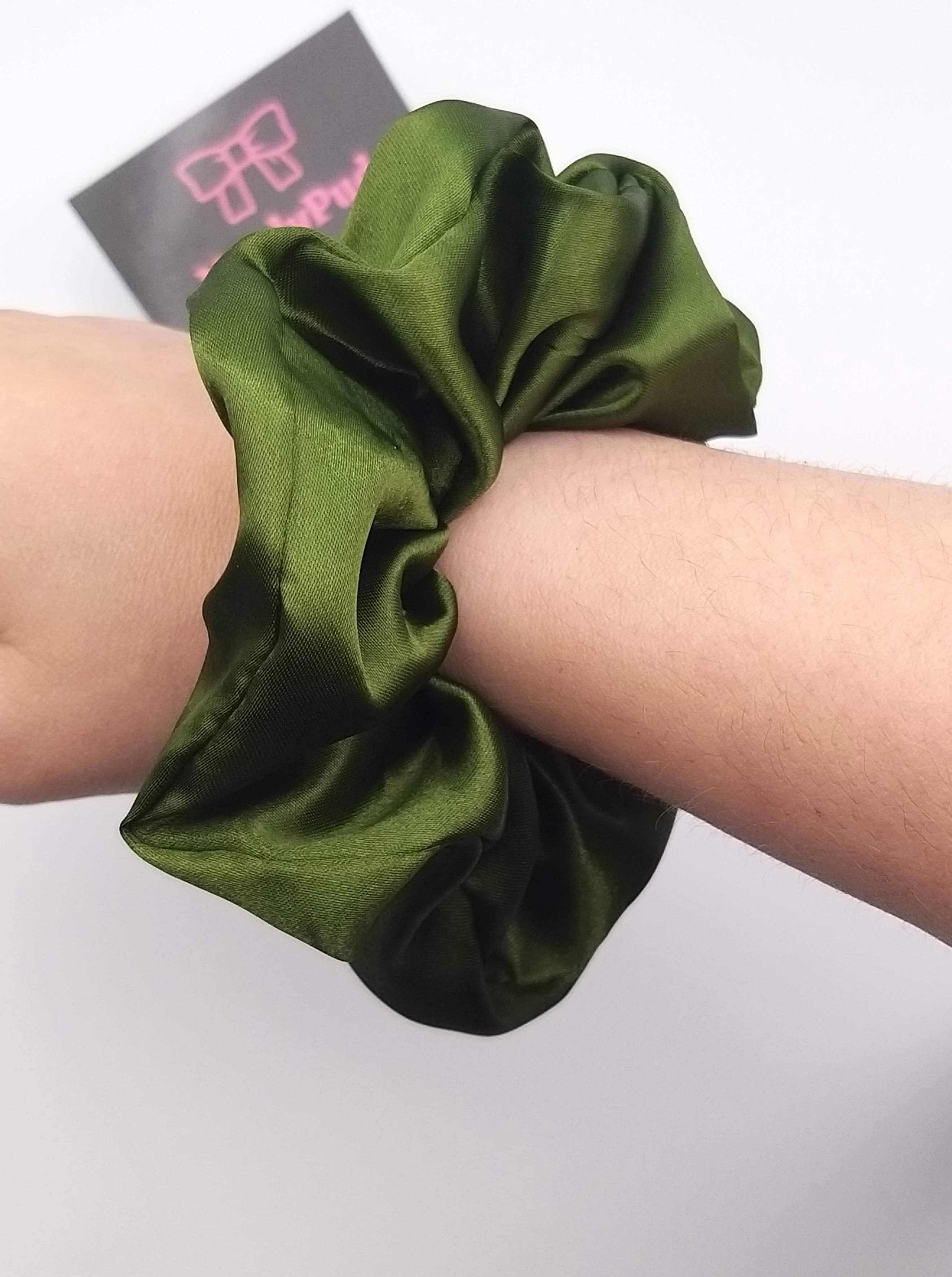 Green scrunchie on a wrist with a blurred background