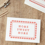 Home Sweet Home Cross Stitch Card for a new home on a wooden table
