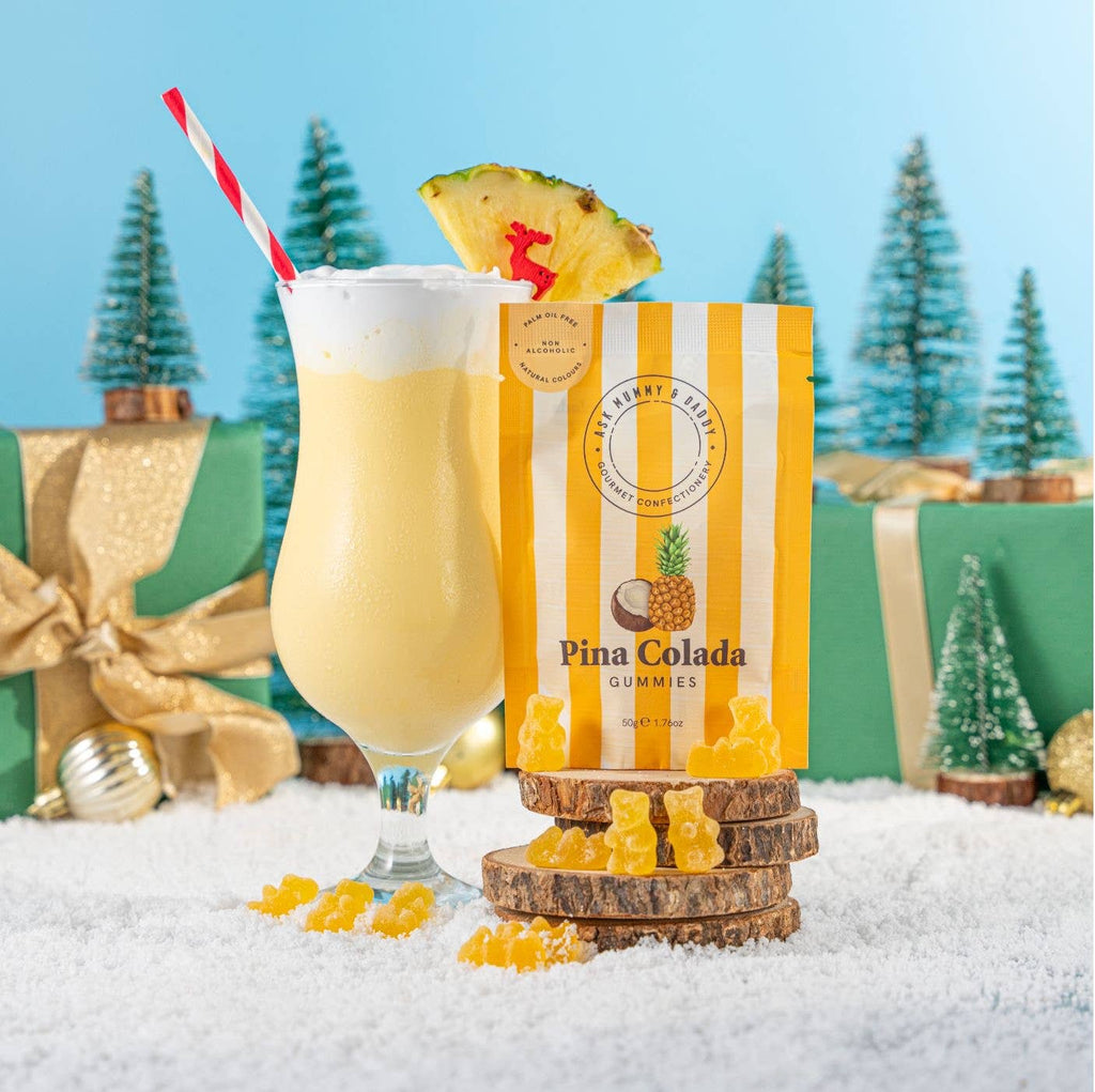 Striped bag of Pina Colada Gummies on a yellow background, styled with a cocktail glass - All Good Things