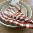 Red gingham napkin in stoneware bowls on wooden table - All Good Things