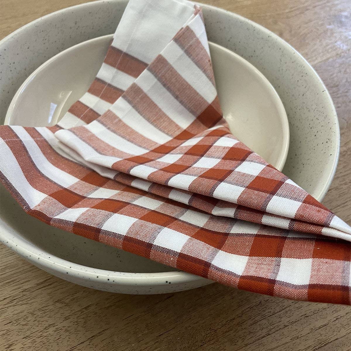 Red gingham napkin in stoneware bowls on wooden table - All Good Things